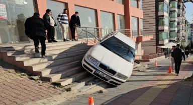 Çorum'da park halindeyken geri kayan otomobil binanın merdivenlerinde asılı kaldı